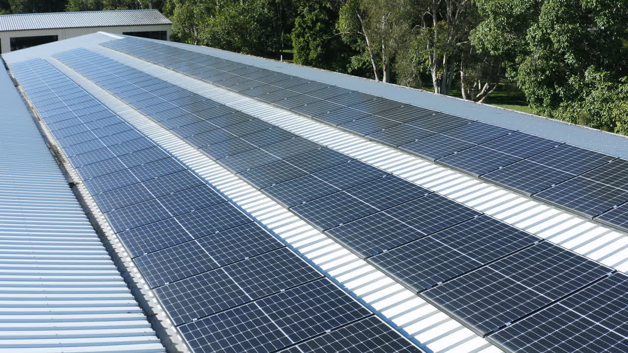 vista panorámica de drones sobre filas de paneles solares en techo de hojalata a la luz del sol, 4k