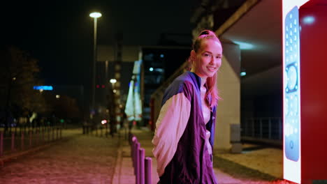 girl standing night lights looking camera with smile. woman enjoy evening time.