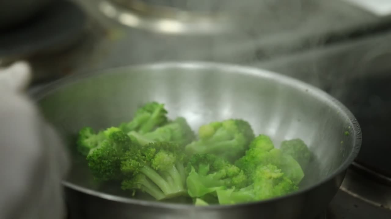 A Chief cooks broccoli on a grill close up shot, insert shot