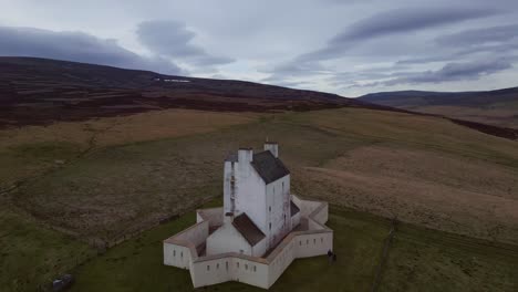 Flug-über-Die-Schottischen-Highlands-Mit-Einer-Malerischen-Weißen-Kirche-Inmitten-Grünbrauner-Wiesen