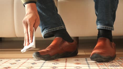 person cleaning brown leather shoes