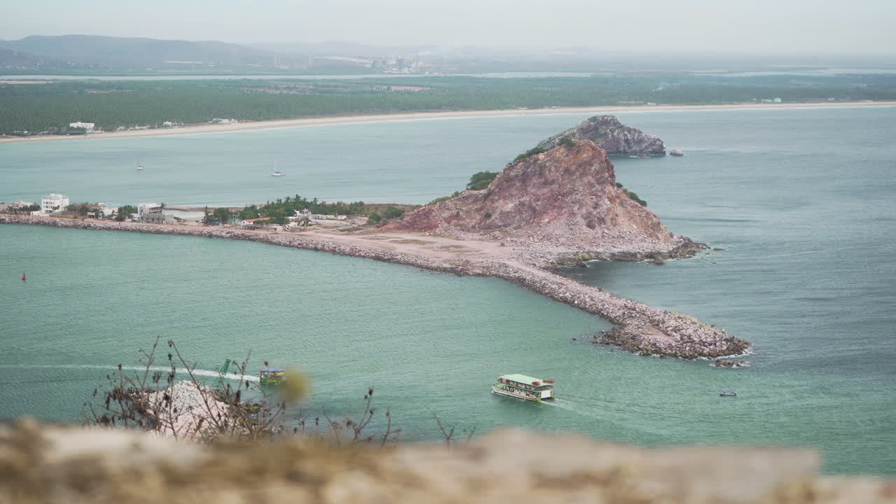 un barco turístico recorre el océano pacífico en mazatlán, sinaloa méxico con montañas y playa al fondo