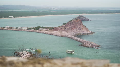 Un-Barco-Turístico-Recorre-El-Océano-Pacífico-En-Mazatlán,-Sinaloa-México-Con-Montañas-Y-Playa-Al-Fondo