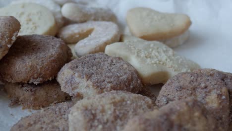 a forward pan showcasing traditional german butterplätzchen, arranged on a white plate, moving toward the center brown cookie, capturing the crumbly texture and authentic look of this treat