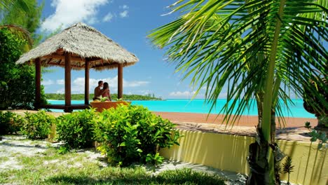 caucasian couple sitting in a tiki beach hut