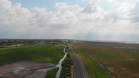 Drohne-Schwebt-über-Autos,-Die-In-Ländlicher-Umgebung-Auf-Der-Autobahnumgehungsstraße-Fahren,-Grüne-Landschaft