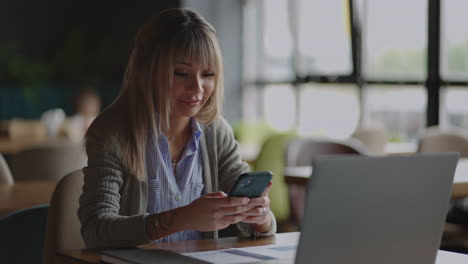 Young-asian-girl-using-her-smartphone-looking-around-with-a-smile.-Modern-devices-gadgets-addiction-being-online.-Social-networks.-Chinese-woman-reading-message-on-smartphone-smile