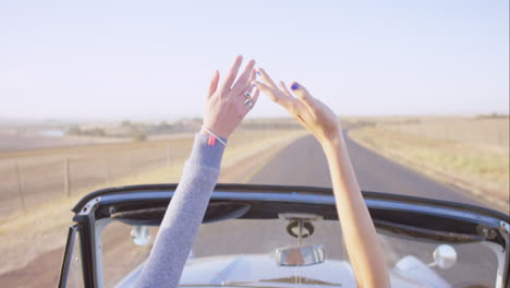 Schöne-Frau-Genießt-Die-Fahrt-Im-Cabrio-Oldtimer-Auf-Roadtrip-Mit-Ausgestreckten-Armen