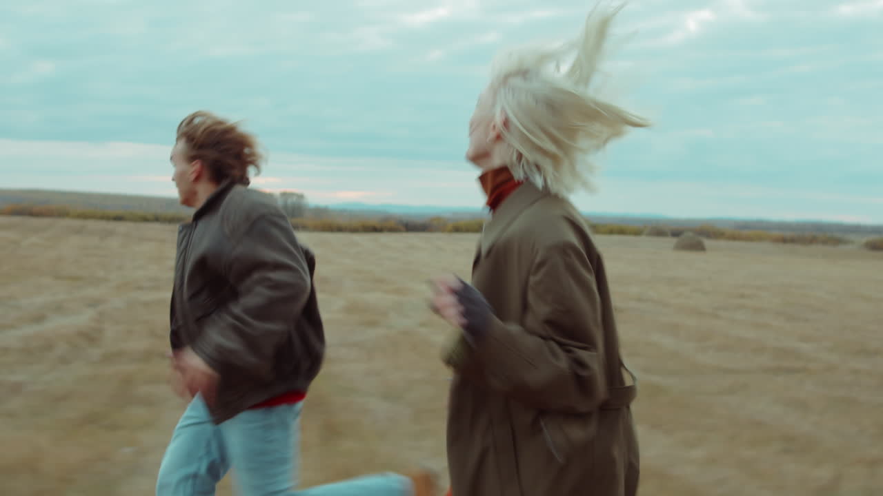 счастливая пара бежит вместе по осеннему полю.