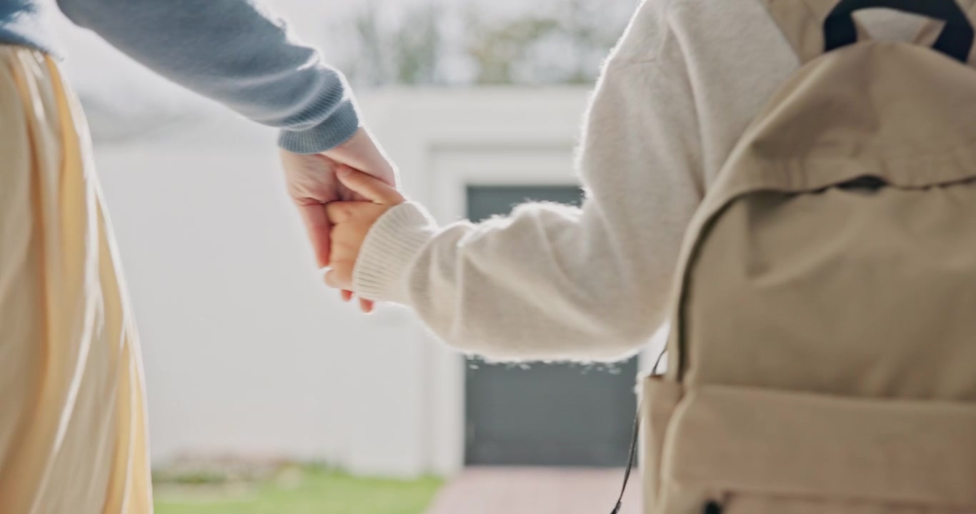 Genitore che tiene per mano un bambino con zaino mentre cammina verso scuola