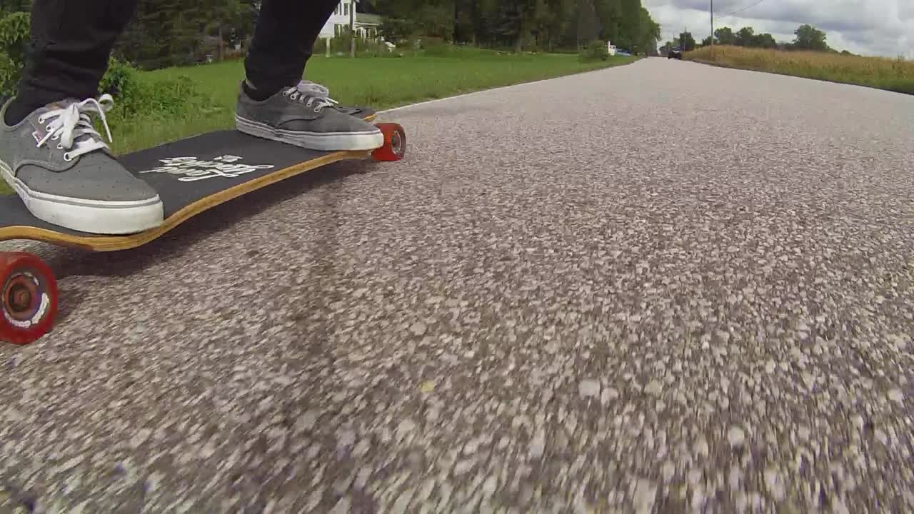 Low angle of person riding a longboard on the road