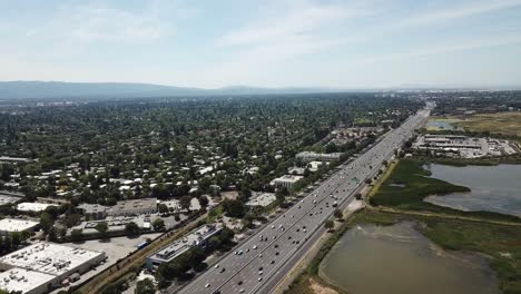 Aerial-view-of-suburbs-dense-trees-rooftop-houses-pine-trees-cars-freeway-101-move-Diagonal