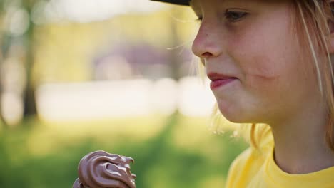 child eating chocolate ice cream in a park