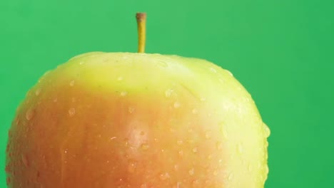 a green apple in water drops rotates on a green background a green apple in water drops rotates on a green background close up