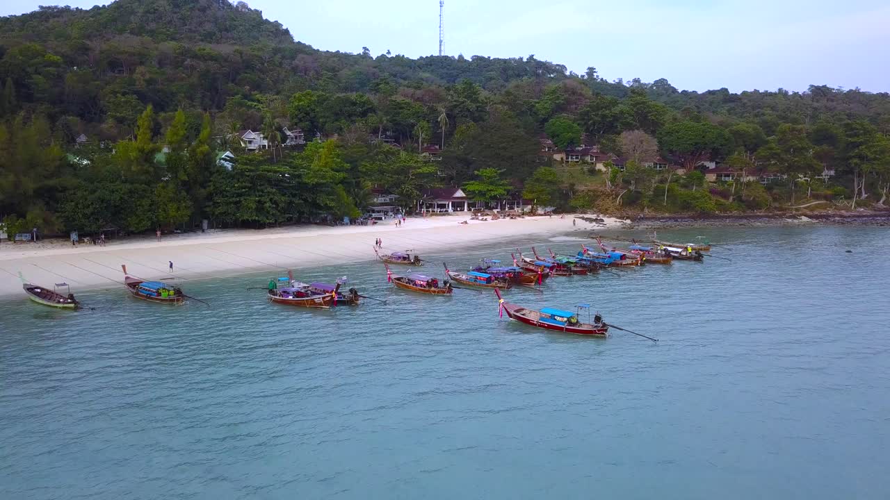 vista aérea de 4k de la playa con botes largos amarrados en la bahía de la isla phi phi, phi phi don, tailandia