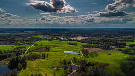 timelapse aerial view of rural landscape with fields, winding roads and cloud shadows