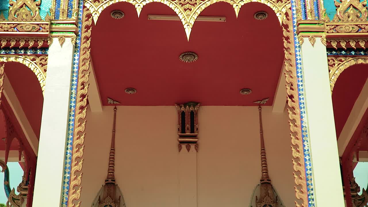 Captivating Panning Down Shot: Admiring the Golden Facade and Buddha Designs of a Traditional Thai Temple at the Front Entrance