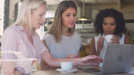 three businesswomen meeting in coffee shop shot through window