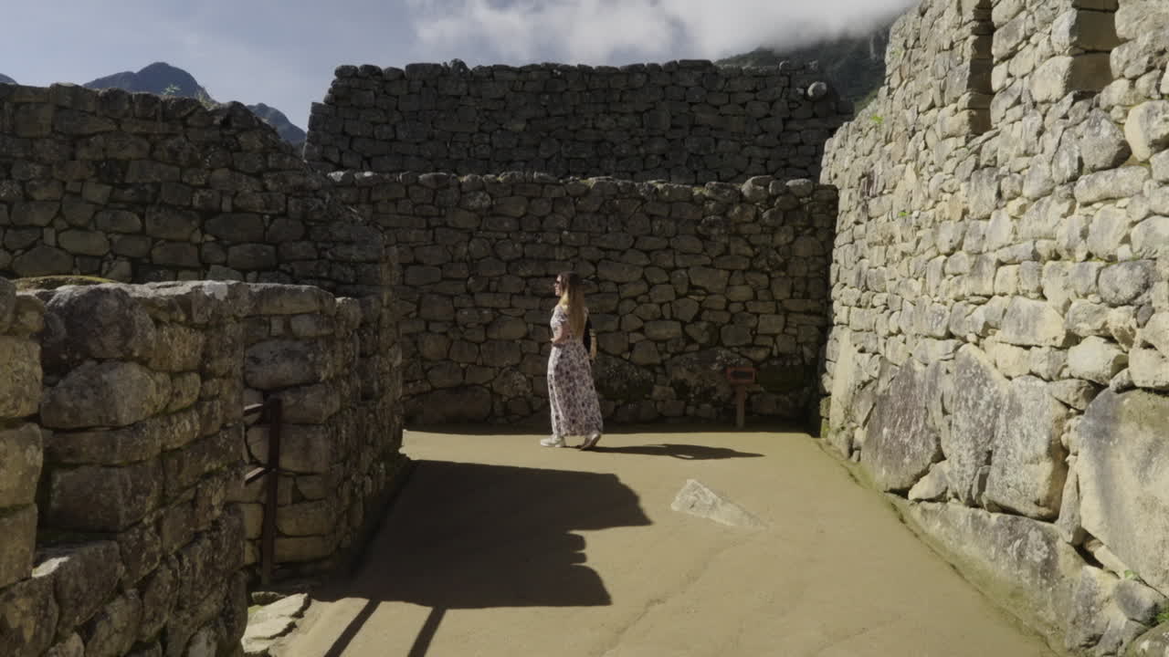 mujer turista camina entre las paredes de roca de machu picchu ruinas de la ciudad perdida