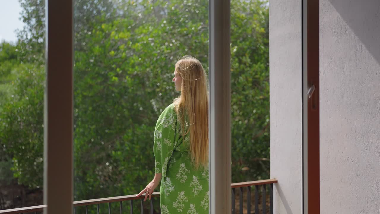 Una donna si trova su un balcone fuori da un hotel o una villa, godendosi la vista tranquilla delle acque paludose e degli alberi circostanti. La scena cattura la natura calma, il relax e un'atmosfera di viaggio serena.