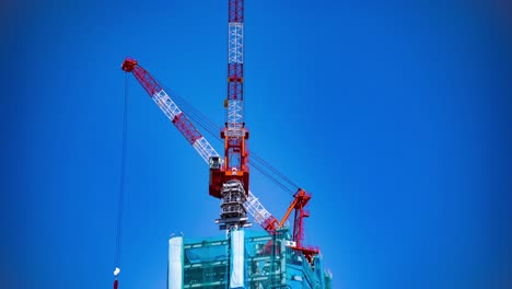 a time lapse of back and forth crane behind the blue sky at the under construction in tokyo tilt