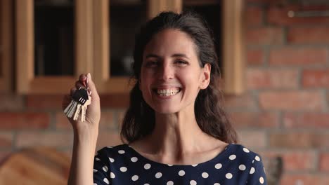 emotional sincere female homeowner showing keys indoors.