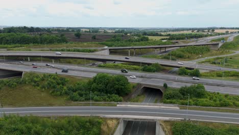 aerial drone orbiting pan view of busy interchange intersection, lots of traffic travelling along the road near rugby england uk, m1 motorway highway