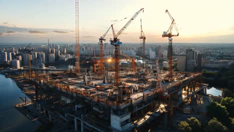 construction site at sunset with cranes overlooking a city skyline