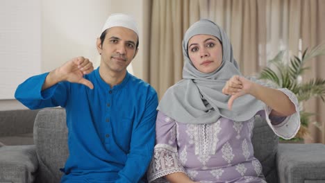 disappointed muslim couple showing thumbs down