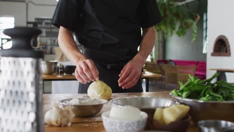 caucasian male chef kneading dough on a kitchen table