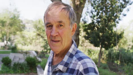 retrato de un anciano caucásico sonriente mirando a la cámara al aire libre en el jardín