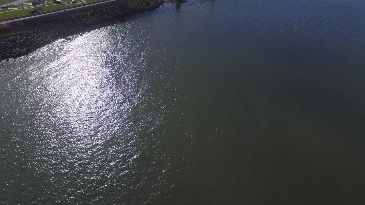 캐나다에서 가장 긴 다리인 컨페더레이션 브리지 (confederation bridge) 위를 드론이 날아다니며 여름날 은 물 위에서 빛이 비치는 공중 영상을 찍습니다.