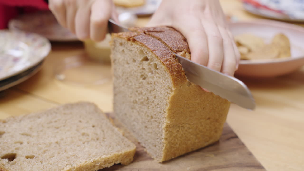 Cutting a slice of bread using a sharp breadknife at the dinner table