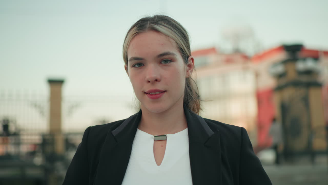 Close up of confident lady in professional attire standing outdoors in urban setting, posing with composed expression, blurred cityscape and people in background