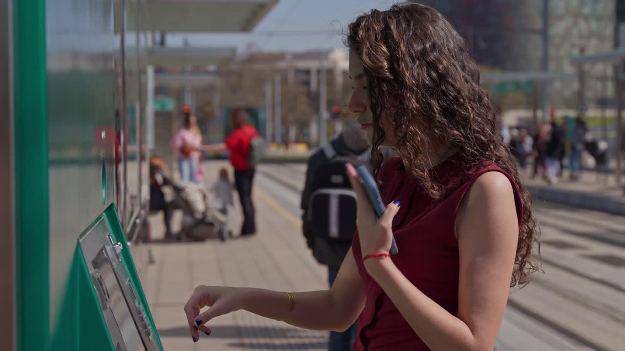 Mujer joven usando una máquina expendedora de billetes en una estación de tranvía