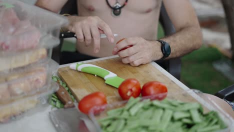 Man prepares vegetables and other ingredients for cooking outdoors