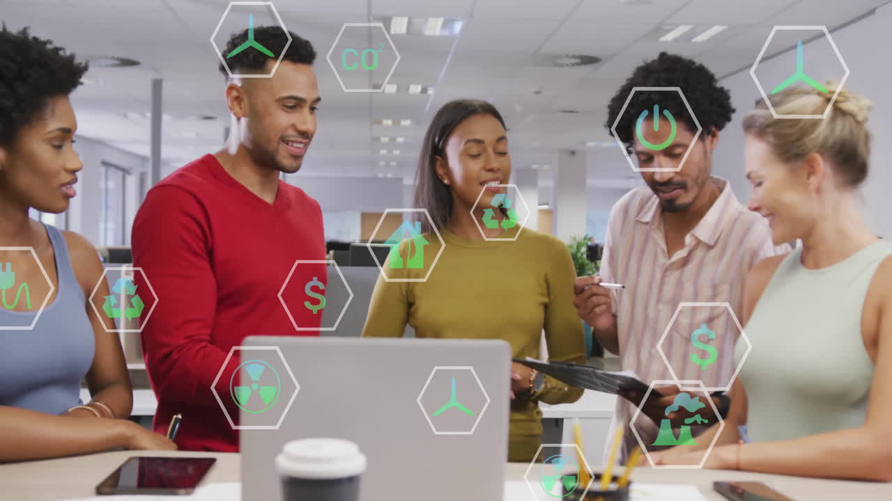 Diverse team collaborating in office with green technology icons overlay animation