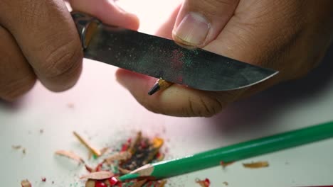 Footage-of-hands-slowly-sharpening-a-pencil-and-some-coloured-pencils-with-a-sharp-knife