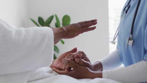 african american female doctor holding senior female patient