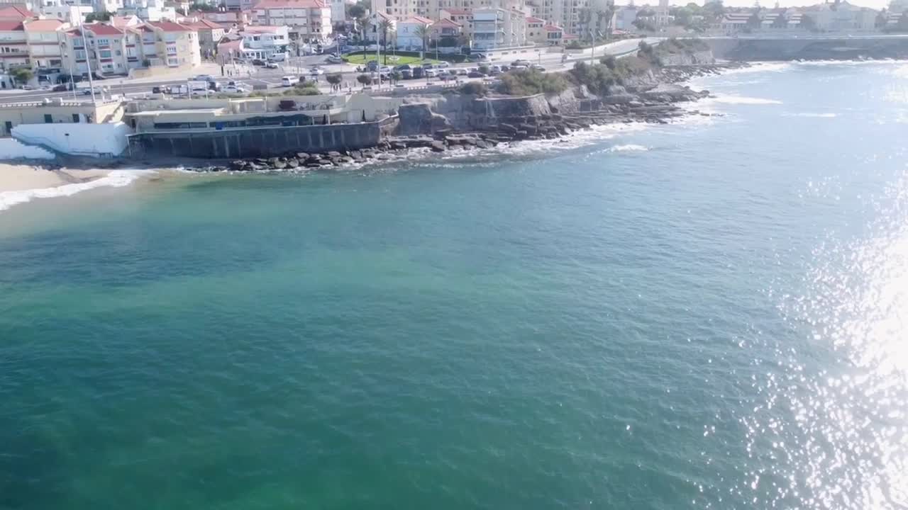 Drone shot panning up revealing cars driving towards the sunset on a costal road in Parede Lisbon Portugal