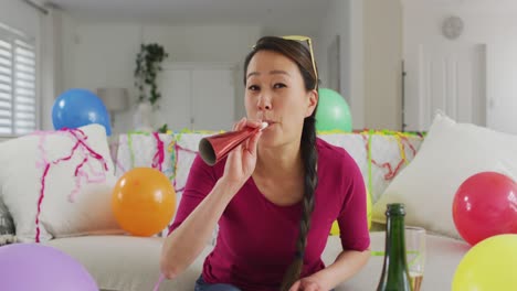 파티 장식품을 가진 행복한 아시아 여성이 새해 전날 노트북 비디오 통화를 하고 있습니다.