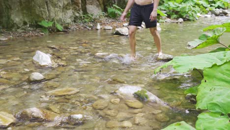 the man walking in the creek in slippers.