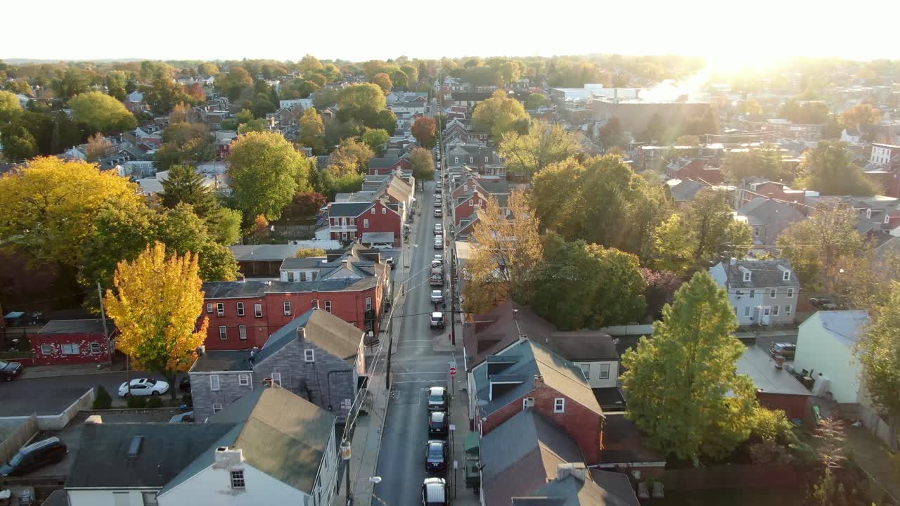 Cinematic establishing shot of homes in urban city, gorgeous sunbeams illuminate autumn trees, fall foliage, Pennsylvania USA