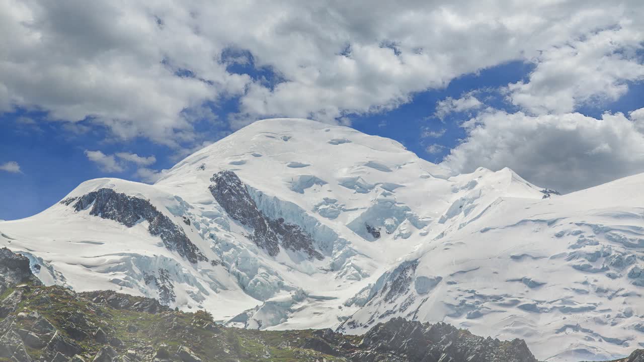 Time lapse of the majestic snow-capped summit of Mont Blanc in the French Alps beneath a dramatic blue sky with white clouds