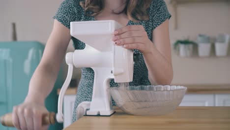 girl-mills-wheat-grains-with-home-grinder-at-wooden-table