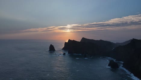 Luftaufnahmen-Von-Drohnen-Zeigen-Majestätische-Berggipfel,-Die-Während-Des-Atemberaubenden-Sonnenuntergangs-Auf-Den-Ruhigen-Meereshorizont-Treffen