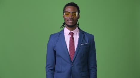 young handsome african businessman with dreadlocks against green background