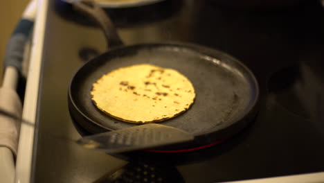 artistic capture of a corn tortilla being flipped on an electric stove