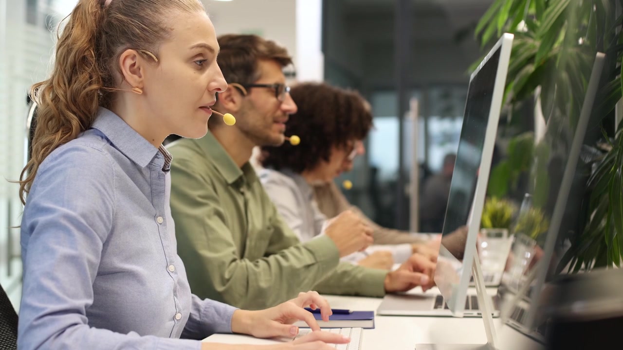 Professional Woman Wearing Headset and Typing on Computer in Office
