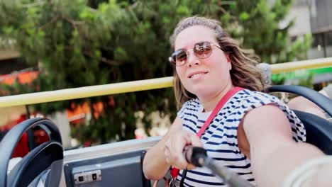 happy woman smiling for a selfie on a tour bus, athens, greece